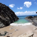 Rocks, sand and blue water on the Lovers Beach, hike away from the road of St Martin