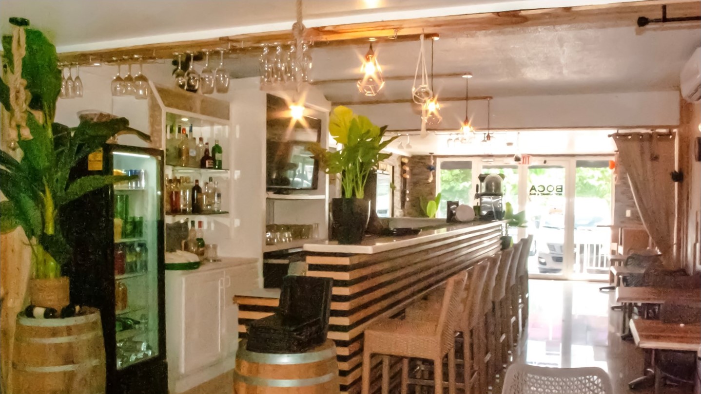 a look on the inside of boca restaurants; you see the bar with stools and plants