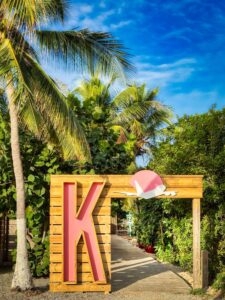 yellow sign of ks beach bar on sint maarten with palmtrees surrounding it