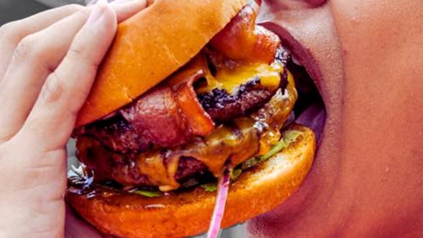 image of a woman biting in a burger from big daddy's restaurant